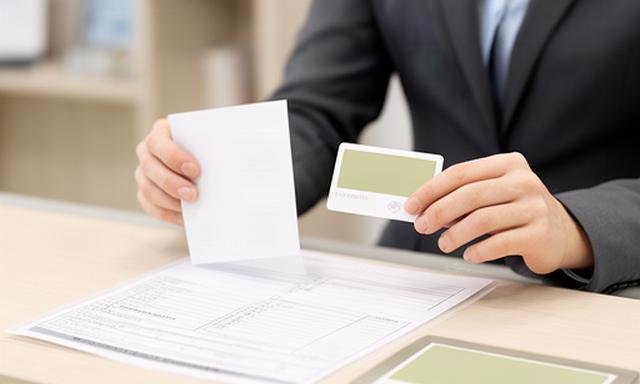 受付担当者が本人からの申請書と本人確認に必要な書類を照合する様子